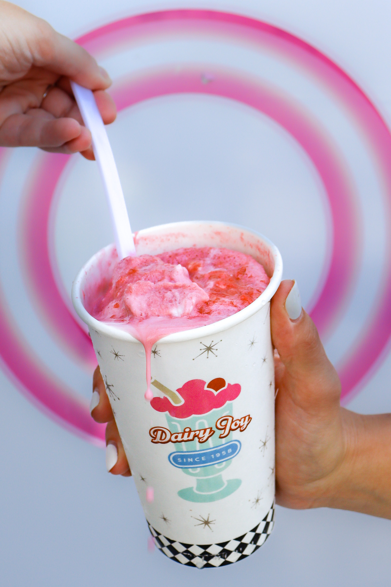 Swirled Soft Serve Cup Close-Up Pink swirl soft serve with spoon and cup logo
