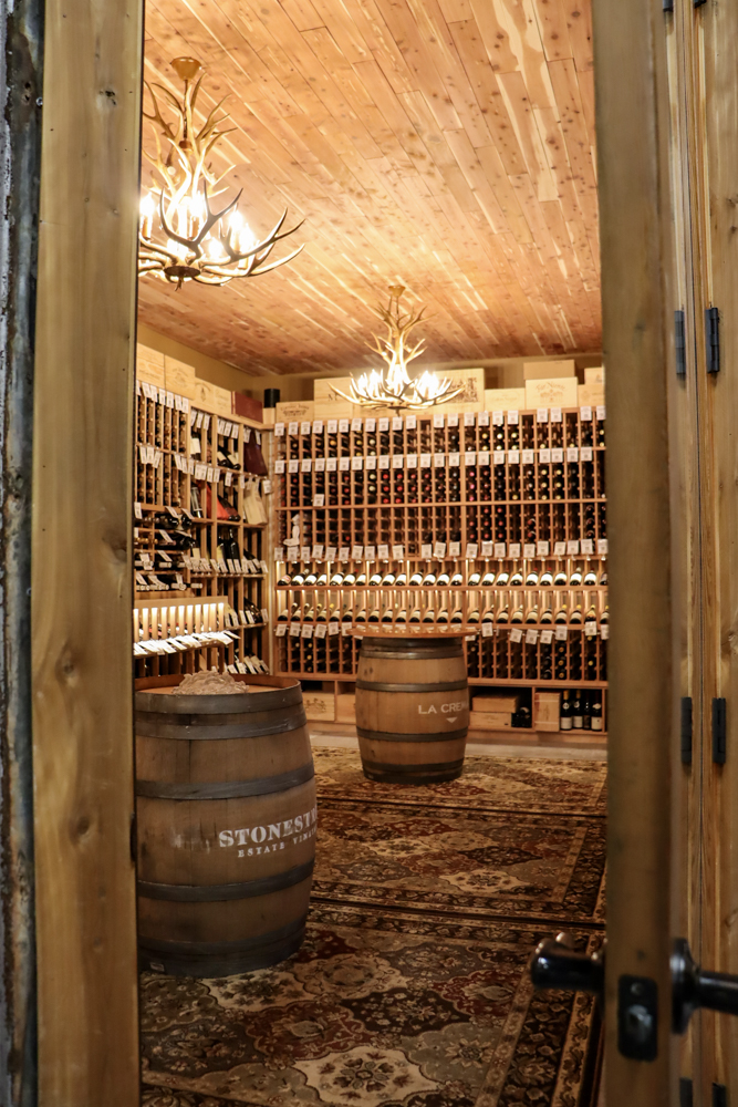 Wine Cellar Interior Photography – Redneck Wine Tampa Wine cellar interior with wooden racks, full wine bottles, barrels, and warm lighting at Redneck Wine Company Tampa