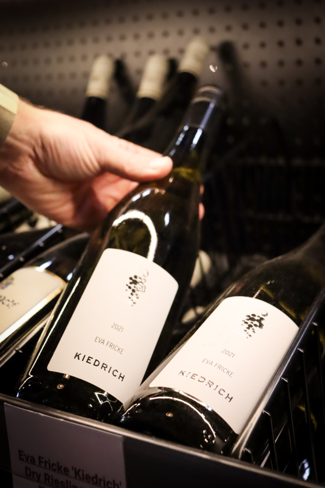 Wine Label Selection – Retail Photography Staff member reading label from a wooden wine shelf