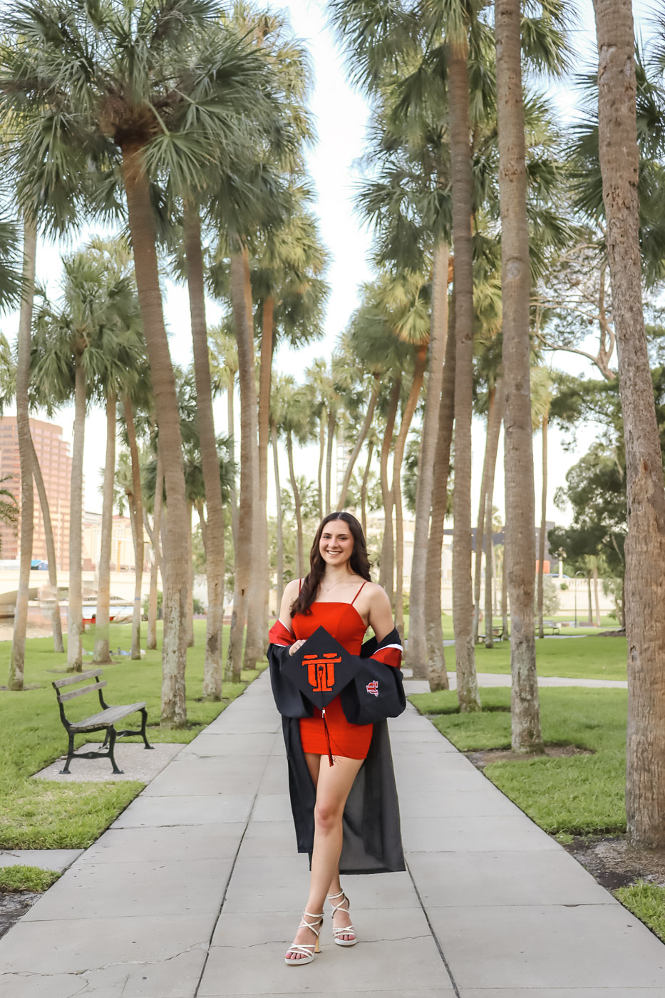 UTampa grad walks confidently into her future in red dress Graduate holding cap walking through University of Tampa campus