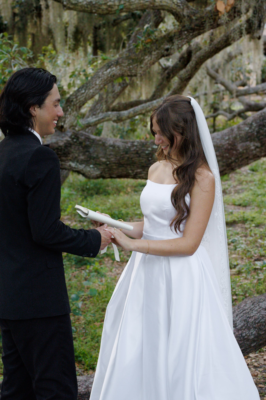 Bride and groom holding hands under a tree