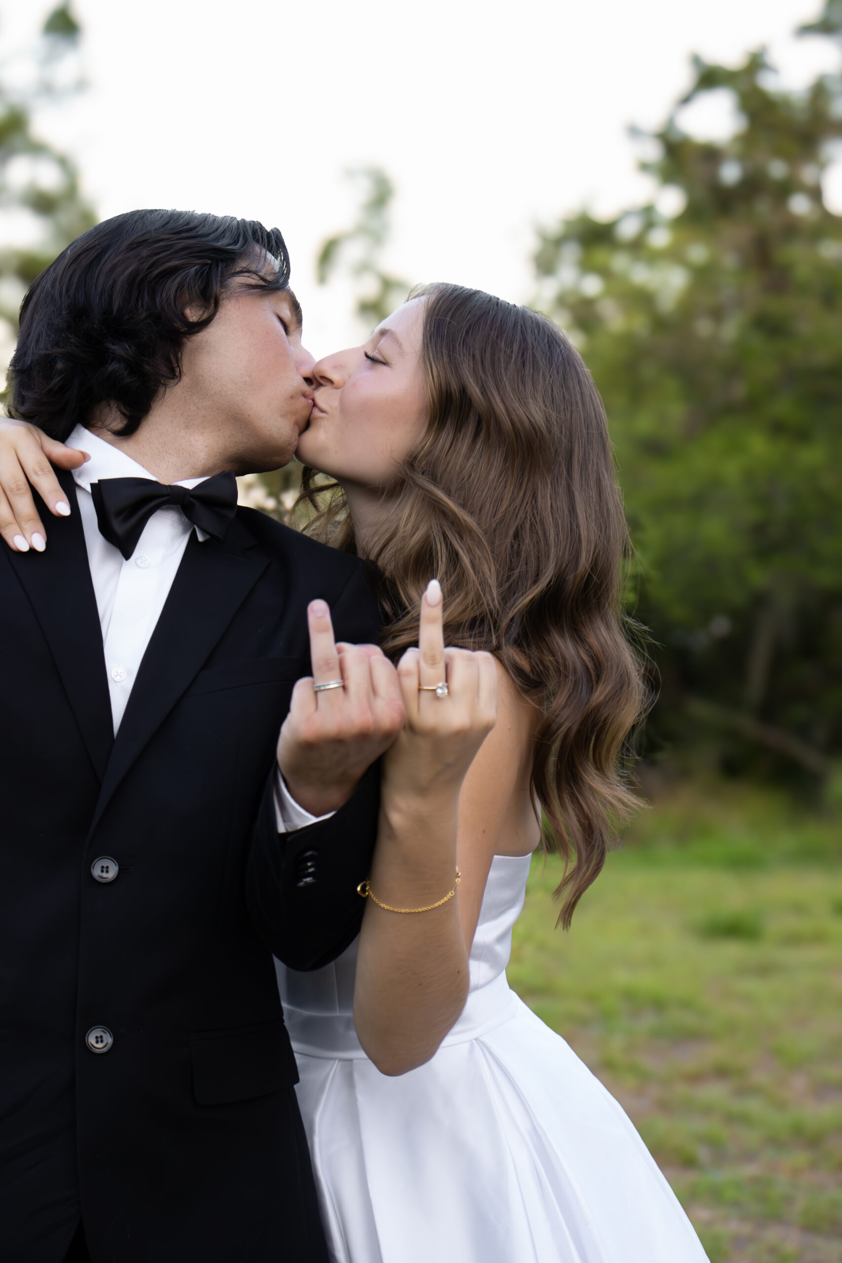 Vibrant Wedding Portrait in Tampa With Bride and Groom Showing Off Rings Bride and groom kissing and showing wedding rings during fun outdoor wedding photo in Tampa